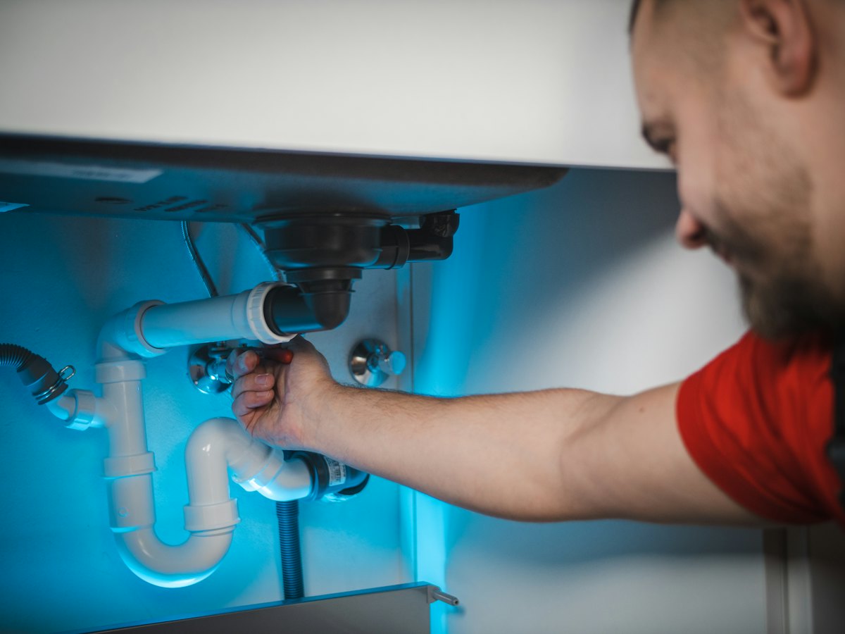 A plumber fixing pipes under a sink